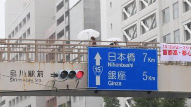 Shinagawa Tokyo 'da yağmurlu bir günde şehir merkezinde yürüyen insanlar.