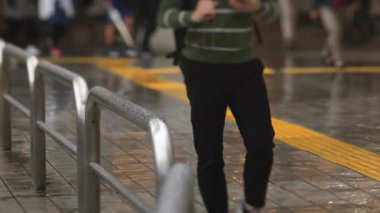 Shinagawa Tokyo 'da yağmurlu bir günde şehir merkezinde yürüyen insanlar.