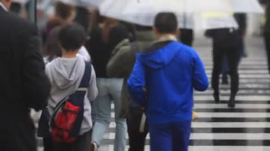 Shinagawa Tokyo 'da yağmurlu bir günde şehir merkezinde yürüyen insanlar.