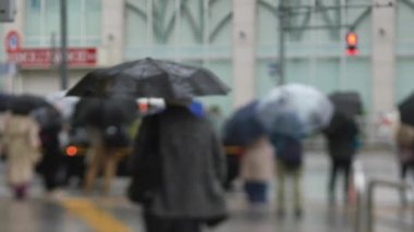 Shinagawa Tokyo 'da yağmurlu bir günde şehir merkezinde yürüyen insanlar.