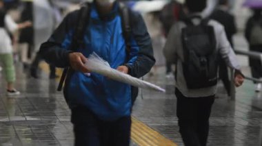 Shinagawa Tokyo 'da yağmurlu bir günde şehir merkezinde yürüyen insanlar.