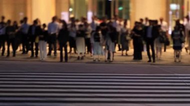 Tokyo 'daki iş kasabasında yürüyen insanların gece manzarası.