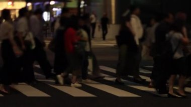 Tokyo 'daki iş kasabasında yürüyen insanların gece manzarası.