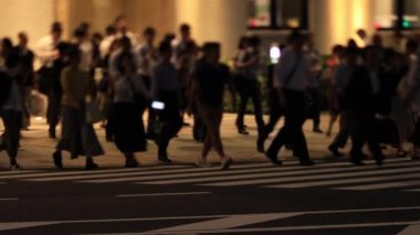 Tokyo 'daki iş kasabasında yürüyen insanların gece manzarası.