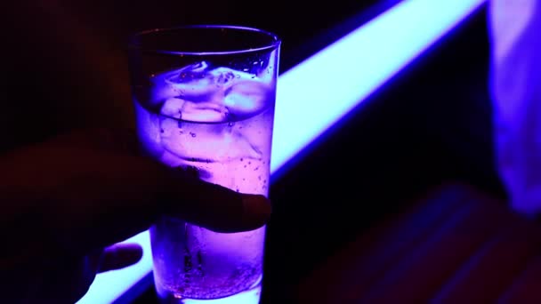 Egy üveg szódavíz neonfényű közelről kézben tartva. — Stock videók
