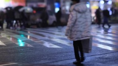 Walking people at the crossing in Shinjuku Tokyo rainy day at night