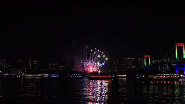 Een avond vuurwerk in de buurt van Rainbow brug bij de stedelijke stad in Tokio breed schot — Stockvideo