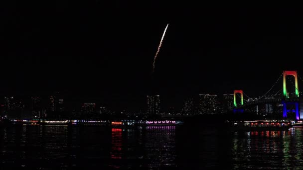 Um fogo de artifício noturno perto da ponte do arco-íris na cidade urbana de Tóquio tiro largo — Vídeo de Stock