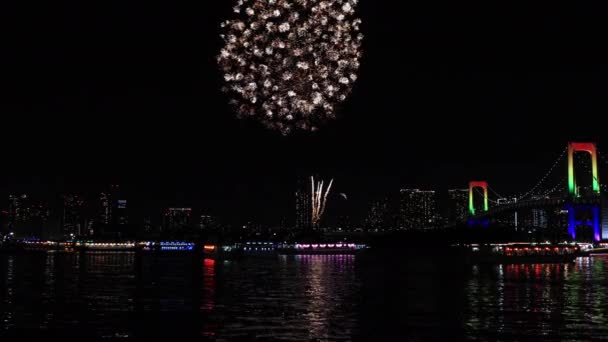 Een avond vuurwerk in de buurt van Rainbow brug bij de stedelijke stad in Tokio breed schot — Stockvideo