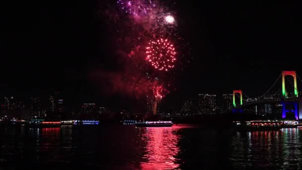 Um fogo de artifício noturno perto da ponte do arco-íris na cidade urbana de Tóquio tiro largo — Vídeo de Stock