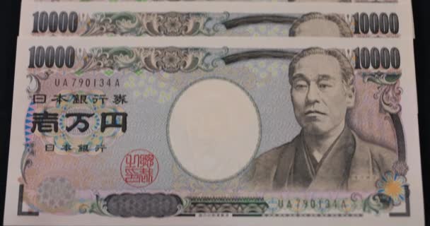 Japanse valuta 100.000 yen op de zwarte achtergrond kantelen — Stockvideo