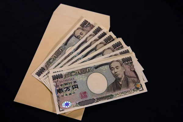 Moeda japonesa 100.000 ienes com envelope no fundo preto — Fotografia de Stock