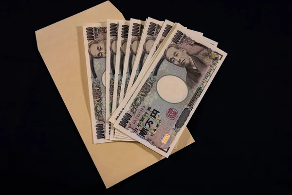 Japanische Währung 100.000 Yen mit Umschlag auf schwarzem Hintergrund — Stockfoto