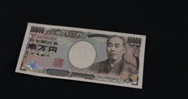 Siyah arka planda Japon para birimi elle 100.000 yen sayılıyor.