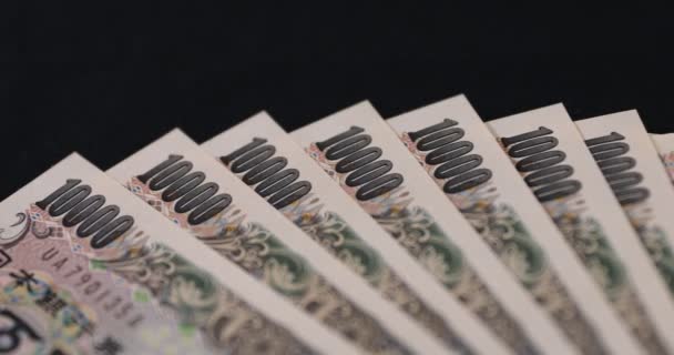 Japanse valuta 100.000 yen op de zwarte achtergrond panning — Stockvideo