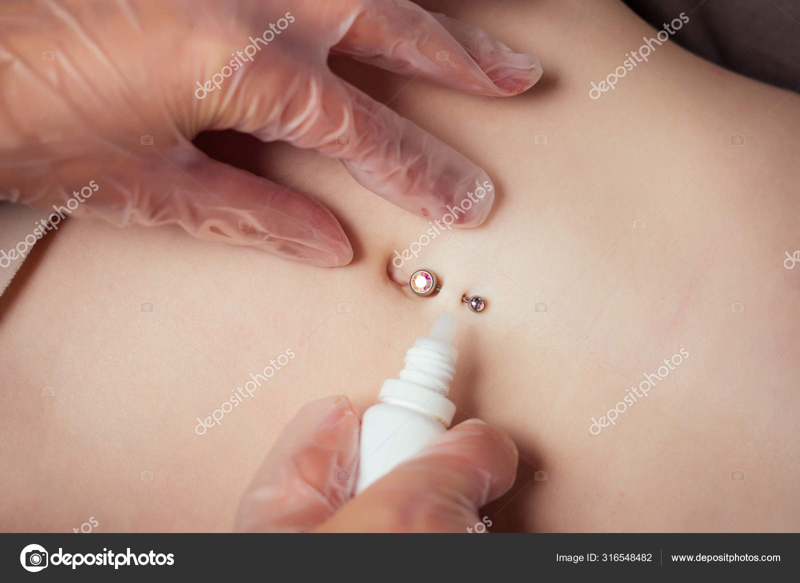 가슴에 붕대를 감고 티타늄 피어싱을 한 젊은 여성의 배로 배꼽을 관통하는 고무장갑을 끼고 있다. 배꼽 피어싱 과정 — 스톡 사진 ©  yurakrasil #316548482, image size:1600x1167