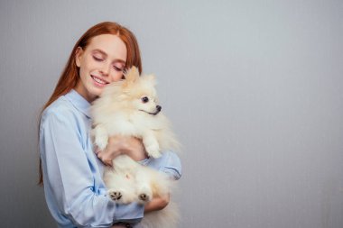 Kızıl saçlı kız evde tükürük yumağına aşık oluyor. Pencerede gün batımı var.