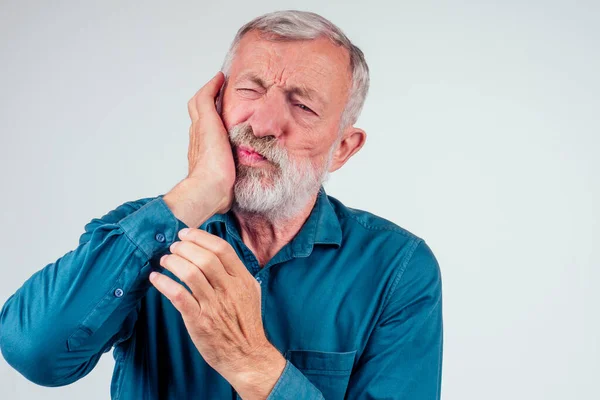 Hombre anciano infeliz con los ojos cerrados sosteniendo un fondo blanco aislado de mejillas, fuerte dolor en la caída del diente. — Foto de Stock