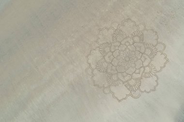 a large mandala painted on the sand on the ocean shore. clipart