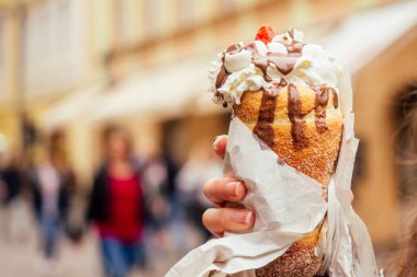 Prag caddesinde vanilya kremalı ve çilekli geleneksel Çek tatlısı Trdelnik 'i iştah yer.
