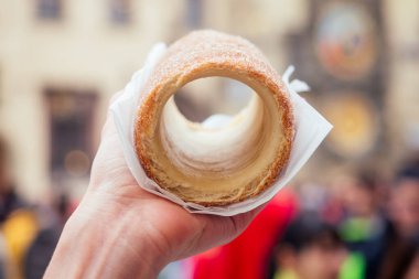 İştahlı bir kadın Prag caddesinde geleneksel Çek tatlısı Trdelnik yiyor.