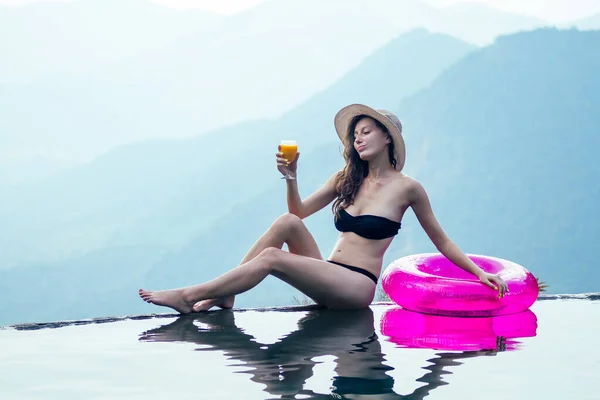 Chica relajante en rosquilla inflable en la piscina infinita en Goa India resort con copa de cóctel — Foto de Stock