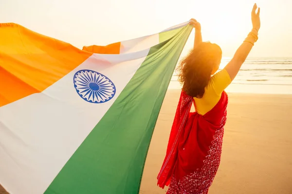 Schöne Frau mit indischer Flagge trikolore, trägt roten Sari der Tradition am Strand von Goa — Stockfoto