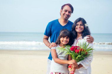 Genç Hintli aile güzel bir yaz günü Goa 'da kumsalda gül buketiyle dinleniyor.