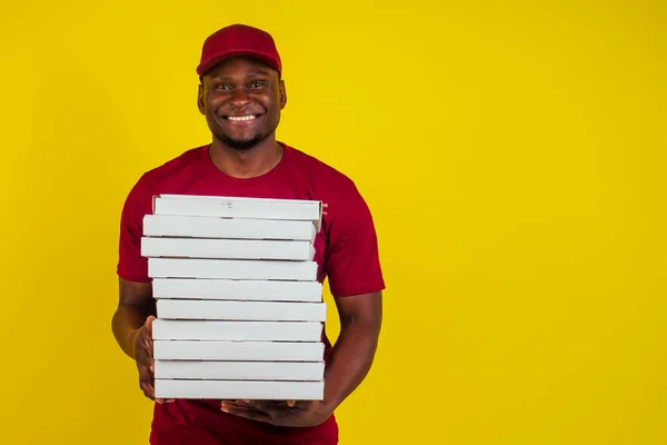 Paketi olan, kırmızı tişörtlü ve sarı şapkalı Afro-Amerikalı bir teslimatçı. Fast food konsepti. — Stok fotoğraf
