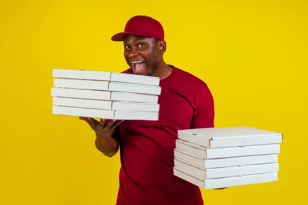 Paketi olan, kırmızı tişörtlü ve sarı şapkalı Afro-Amerikalı bir teslimatçı. Fast food konsepti. — Stok fotoğraf