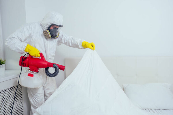 Baby room cleaning .Worker spraying insecticide in bedroom