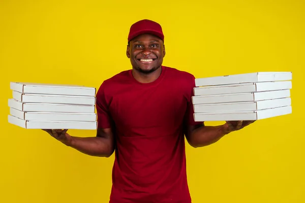 Paketi olan, kırmızı tişörtlü ve sarı şapkalı Afro-Amerikalı bir teslimatçı. Fast food konsepti. — Stok fotoğraf