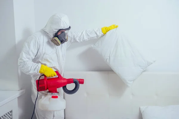 Trabalhador de controle de pragas deitado no chão e pulverizando pesticidas no quarto — Fotografia de Stock