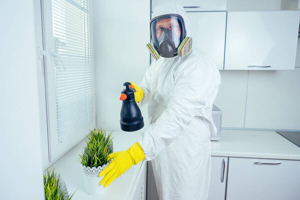 работник по борьбе с вредителями стоять с распылителем на кухне
