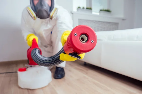 Καθαρισμός βρεφικών δωματίων.Εργάτης ψεκάζει εντομοκτόνο στην κρεβατοκάμαρα — Φωτογραφία Αρχείου
