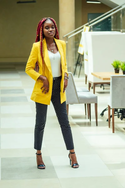 Креативний стиліст афроамериканська молода жінка з канекалонським волоссям довгі афро-коси в жовтому піджаку. красивий дизайнер одягу позує в робочому кабінеті ремесла — стокове фото