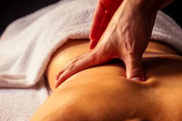 Masajista manos haciendo masaje de espalda al cliente en el centro de spa en habitación oscura — Foto de Stock