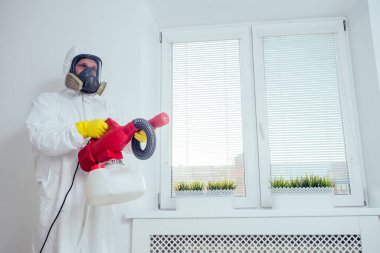 Bebek odası temizliği. İşçi yatak odasında böcek ilacı sıkıyor.