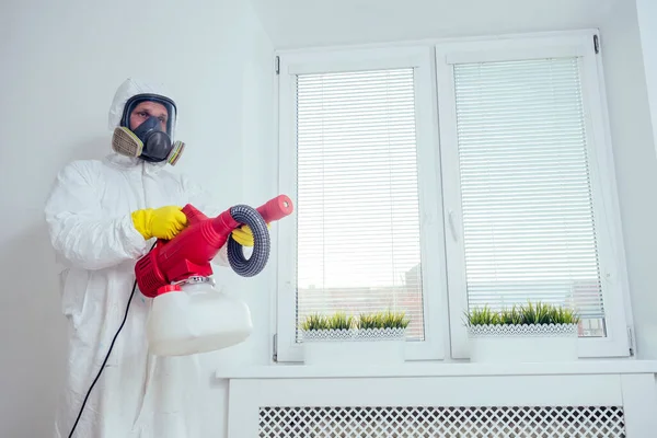 Καθαρισμός βρεφικών δωματίων.Εργάτης ψεκάζει εντομοκτόνο στην κρεβατοκάμαρα — Φωτογραφία Αρχείου