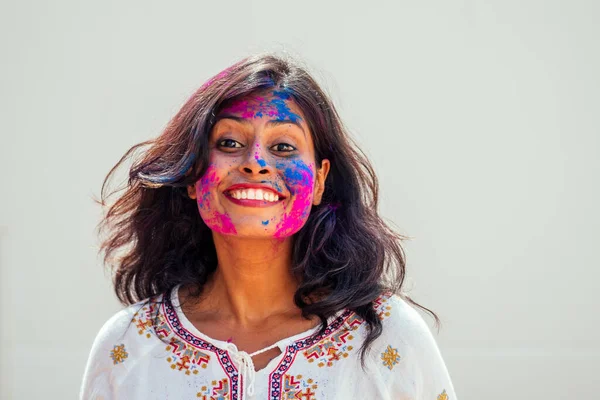 Festival Holi de Colores. Retrato de chica india feliz en color holi. ella bailando y divirtiéndose en fondo de estudio de pared blanca —  Fotos de Stock