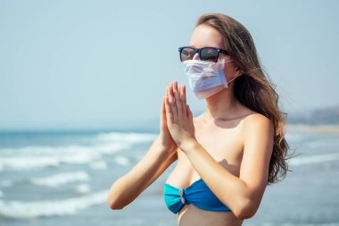 Tropik plajda maske takan bir kadın. Korona virüsünü önleme kavramı