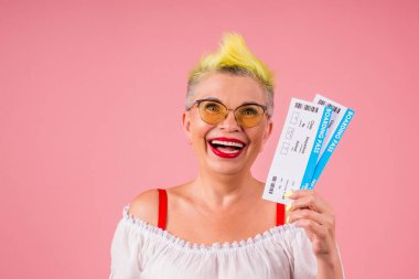 Beyaz, eski, şık sarı saçlı, güneş gözlüklü, elinde pasaport ve pembe stüdyo arka planında uçuş bileti olan bir son sınıf öğrencisi. Sonsuza dek kırmızı ruj.