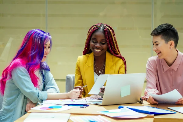 African american designer sitting with multi-colored pink blue long hair girl giving new ideas about project in conference room — Stock Photo, Image