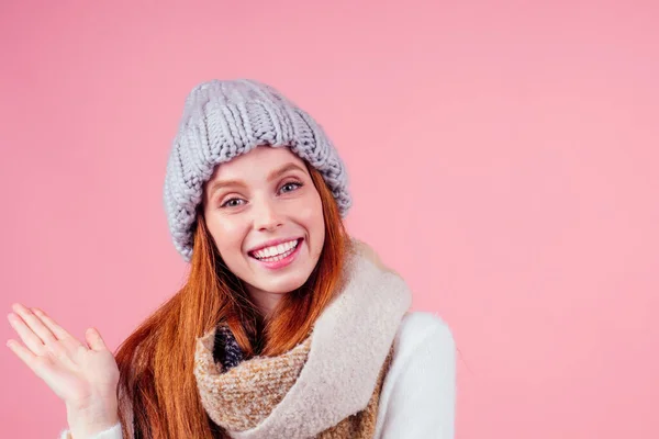 Mulher ruiva ruiva usar chapéu de lã elegante, suéter e cachecol olhando para a câmera e apontando os dedos para copyspase em estúdio fundo rosa — Fotografia de Stock