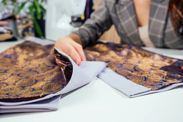 Retrato de uma costureira em uma jaqueta quadriculada trabalhando em seu estúdio de costura, ela mostrando dentro de forro de roupas — Fotografia de Stock