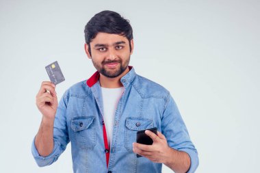 Stüdyonun beyaz arka planında kredi kartı tutan mutlu Hintli erkek.