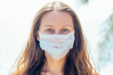 Tropik plajda maske takan bir kadın. Korona virüsünü önleme kavramı