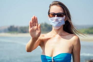 Tropik plajda maske takan bir kadın. Korona virüsünü önleme kavramı