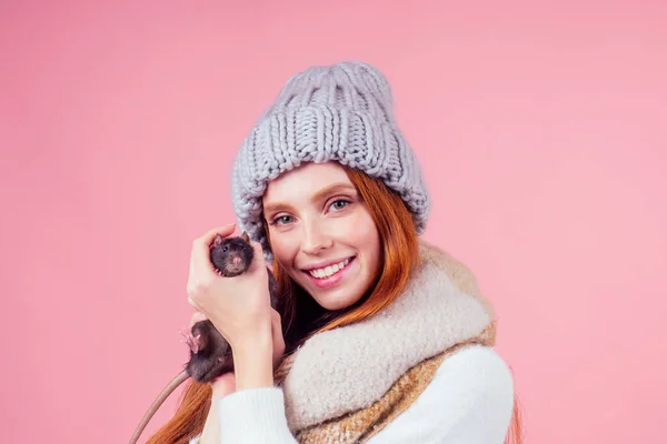 Feliz bela ruiva ruiva boa-loking mulher vestindo chapéu de malha na moda com suéter segurando seu lindo rato macho preto no estúdio rosa fundo — Fotografia de Stock