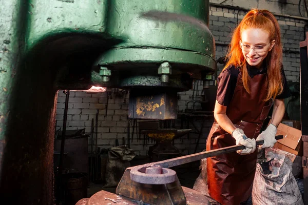 Roodharige roodharige vrouw die smithytools gebruikt in donkere werkplaatsen om hamer hamer details te smeden. concept voor kleine ondernemingen — Stockfoto